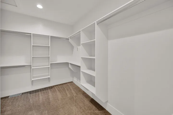 Built-in closet organization system with shelving, hanging rods, and recessed ceiling lighting