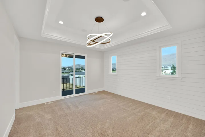 Recessed ceiling lighting, modern chandelier, coffered ceiling, shiplap accent wall, and sliding glass door leading to a balcony