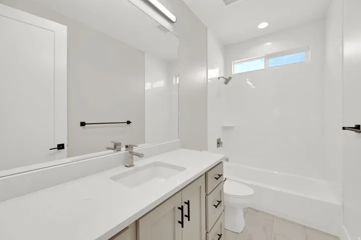 Single vanity with light-toned cabinetry, a white countertop, and an integrated rectangular sink
