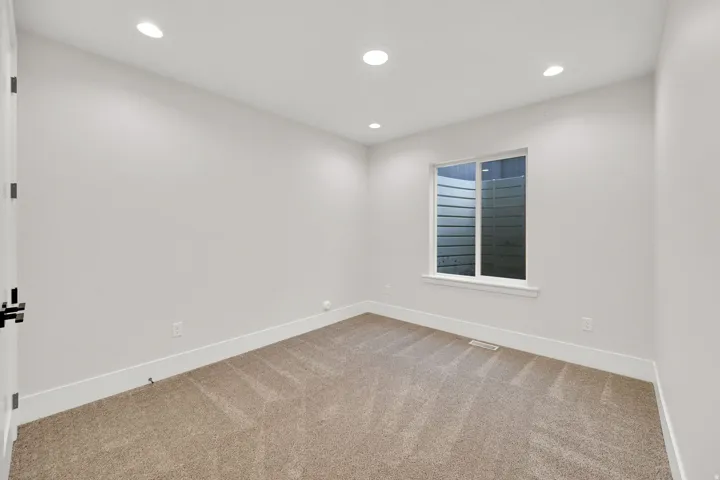 Bright, freshly finished bedroom featuring recessed ceiling lighting, neutral wall finishes, and warm wood-finish flooring