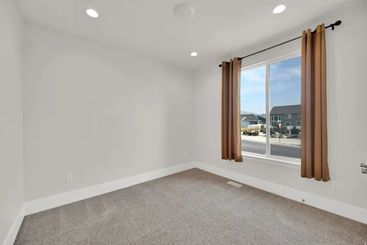 Recessed ceiling lighting, large window with white frame, grey carpeting, and white wall finishes