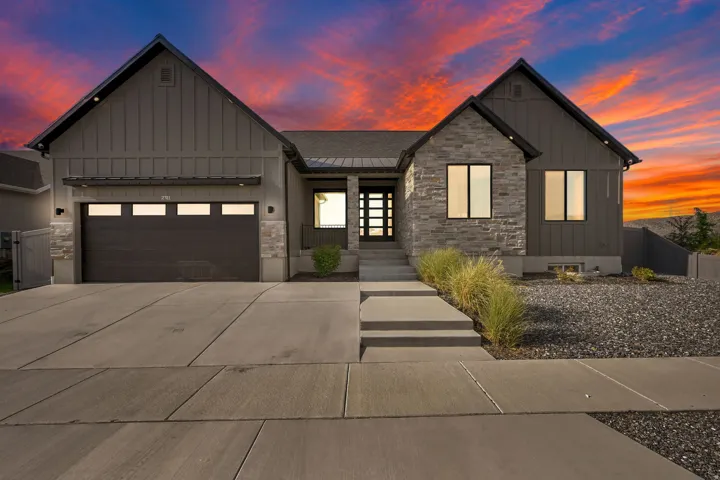 Contemporary exterior featuring board and batten siding, stone accents, a multi-panel garage door with windows, a concrete driveway, and a modern entry door with frosted glass panels