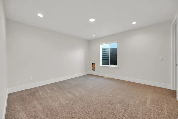 Recessed ceiling lighting, carpet flooring, a window, and white wall finishes