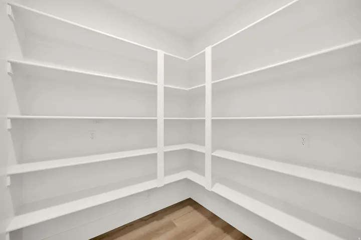 Spacious corner pantry with generous shelving throughout, providing ample storage capacity