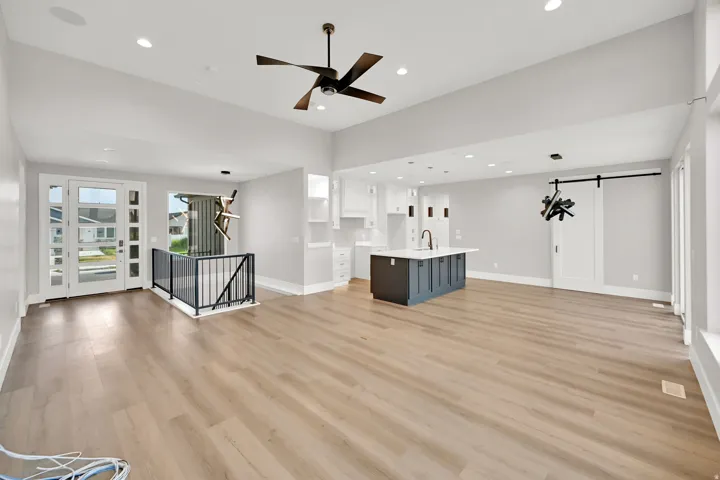 Open-concept living space with wood-finish flooring, recessed lighting, and a modern ceiling fan