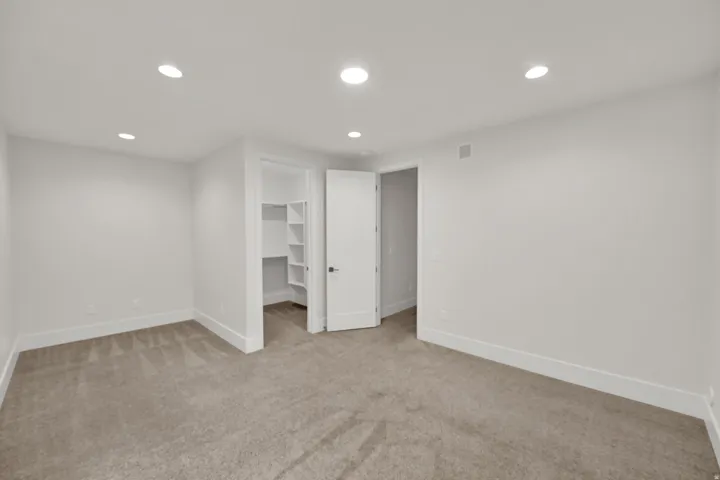 Spacious bedroom featuring neutral wall finishes, recessed ceiling lighting, and neutral-tone carpeting