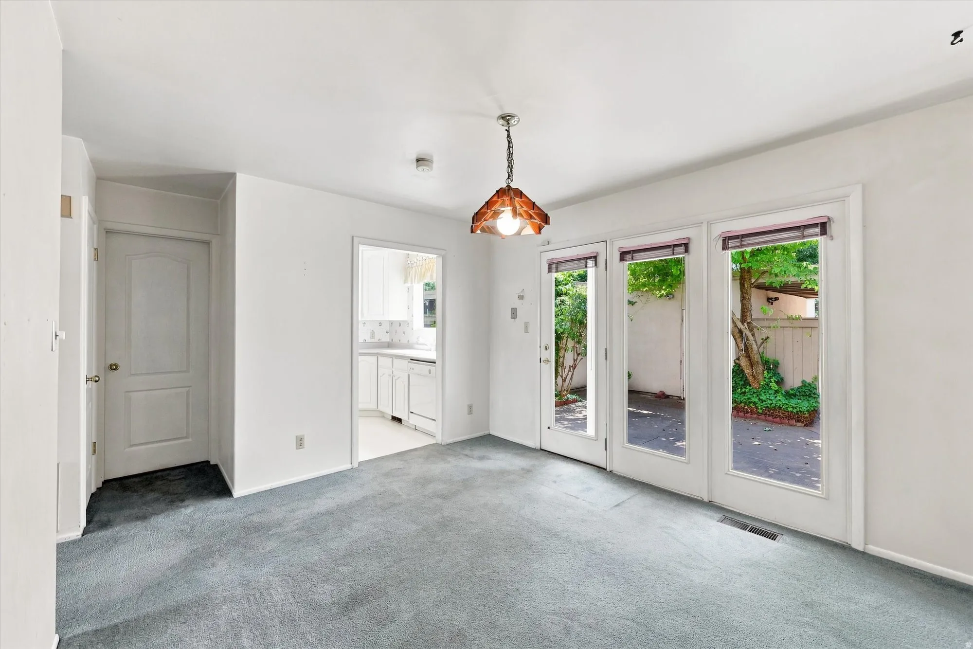 Recessed lighting, ceiling-mounted fixture, and three glass-paneled doors opening to an outdoor patio