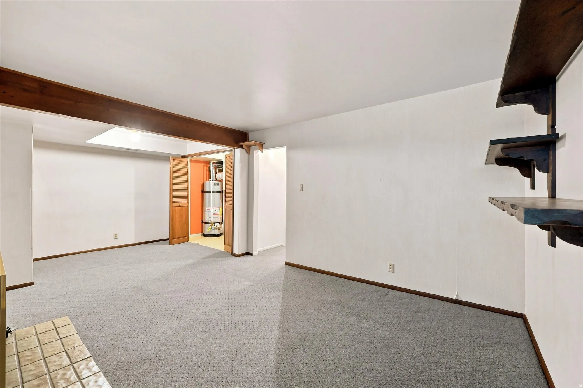 Exposed wood beam, built-in shelving, light gray carpeting, tile hearth, and bi-fold closet doors