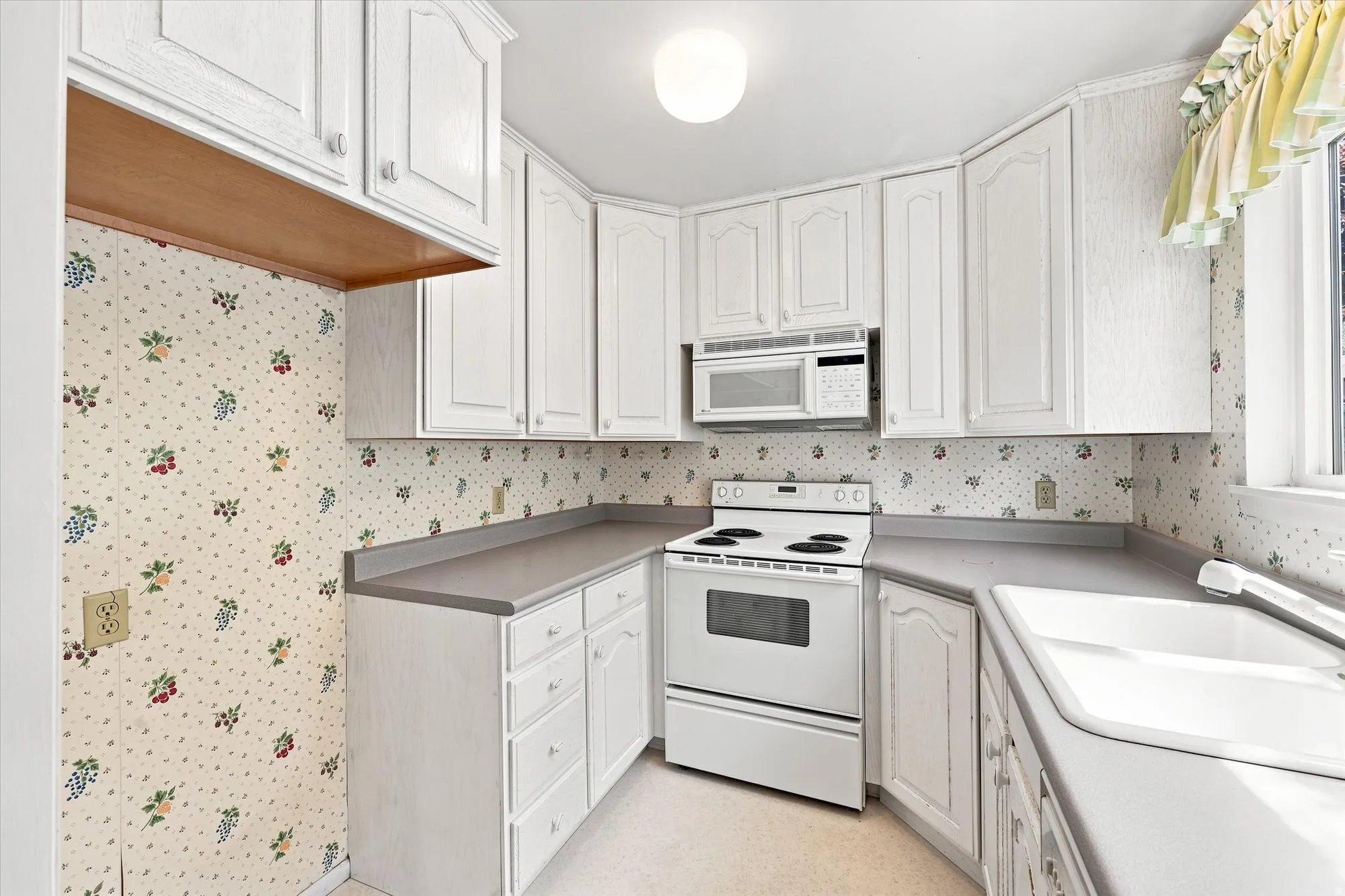 White cabinetry, laminate countertops, integrated sink, and white appliances