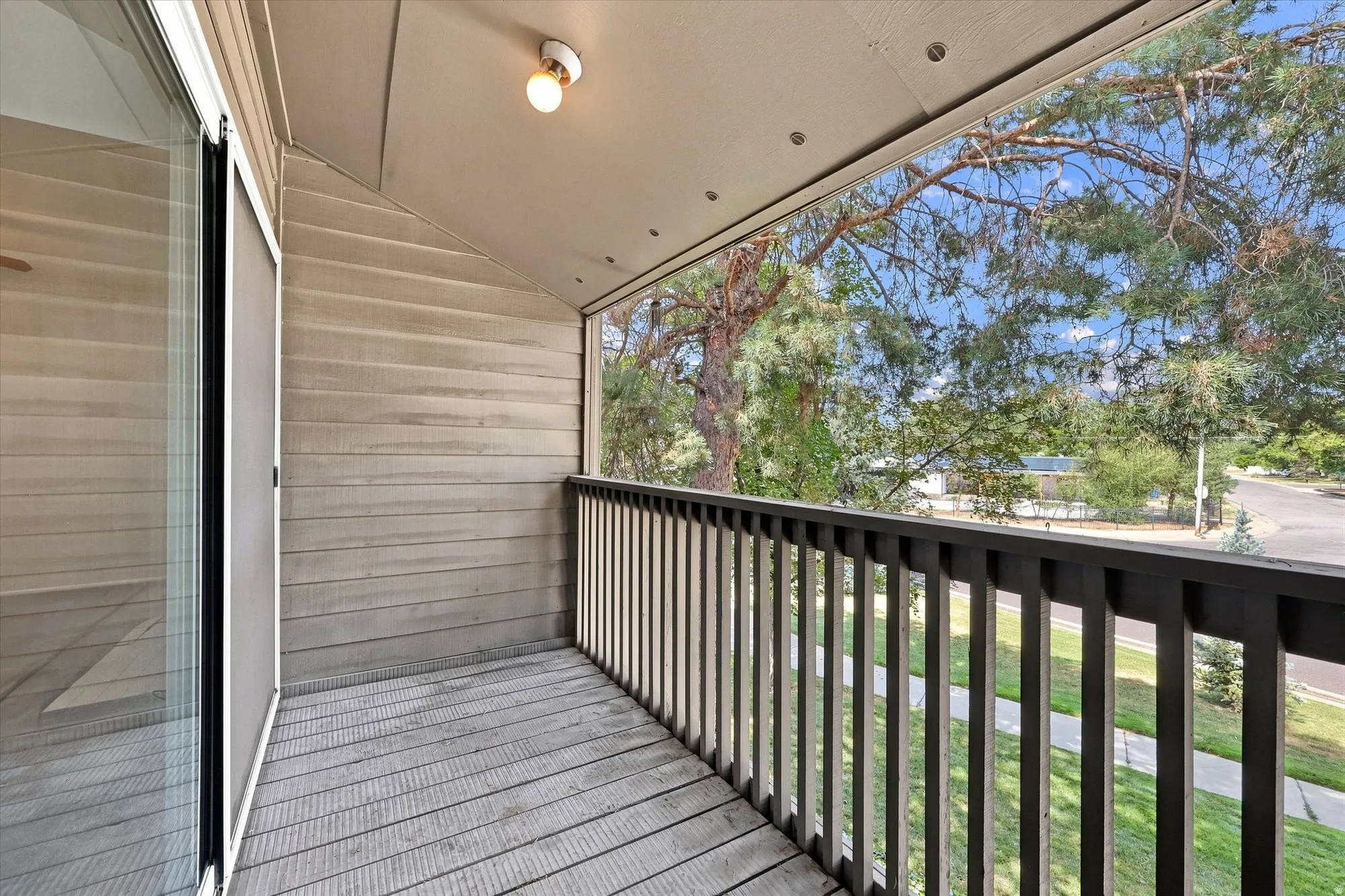 Private balcony featuring wood-finish decking, a black railing, and horizontal siding