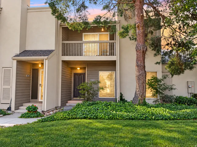 Two-story exterior with a private balcony, covered entryways, mature landscaping, and well-maintained lawn