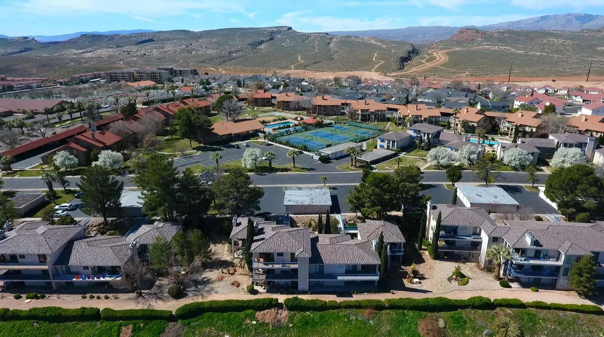Community featuring multiple residential structures, tennis courts, and mature landscaping