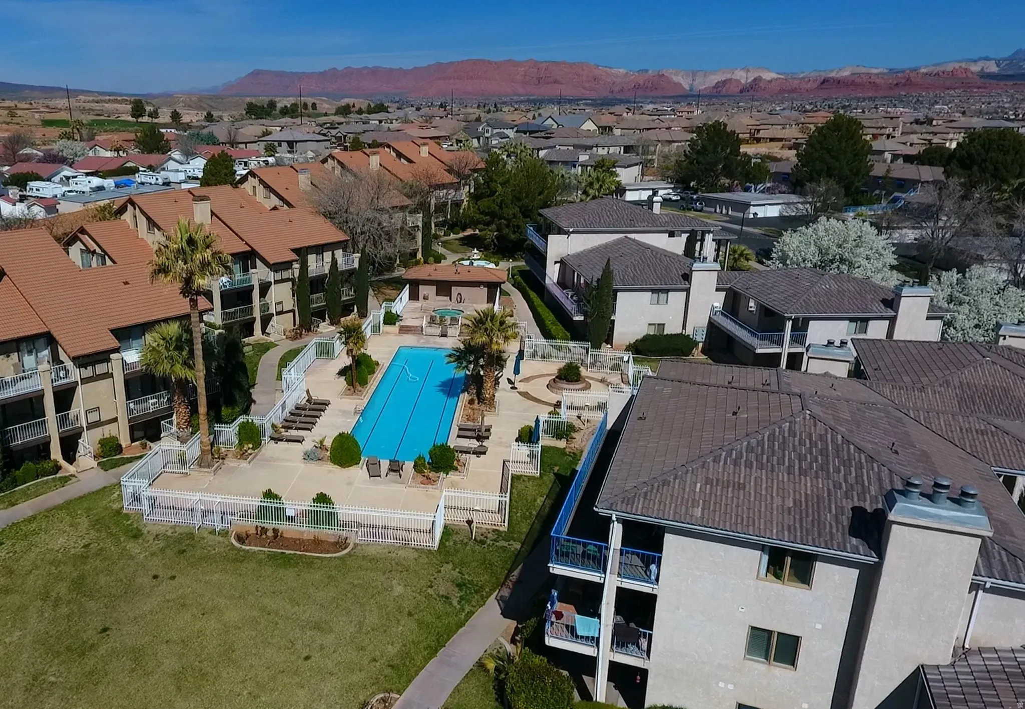 Community swimming pool, spa, and surrounding patio area with lounge seating