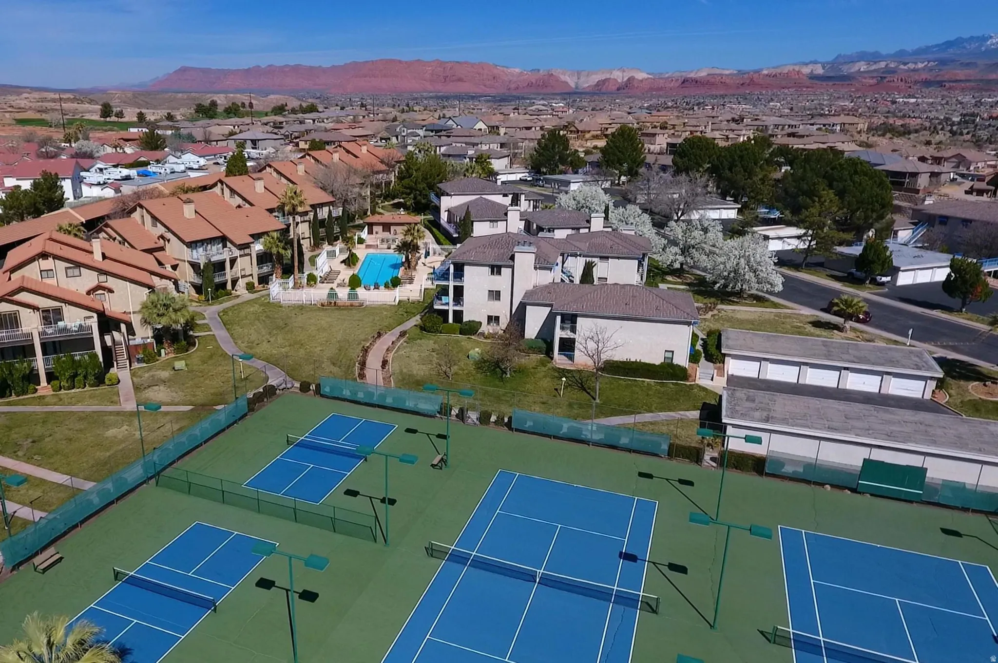 Multiple tennis courts with blue playing surfaces