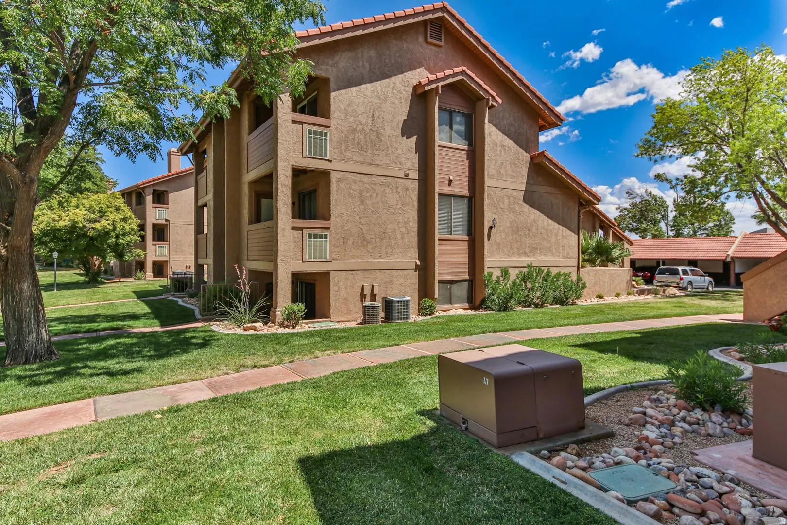 Multi-story building featuring stucco exterior, red tile roof, and individual balconies with railings