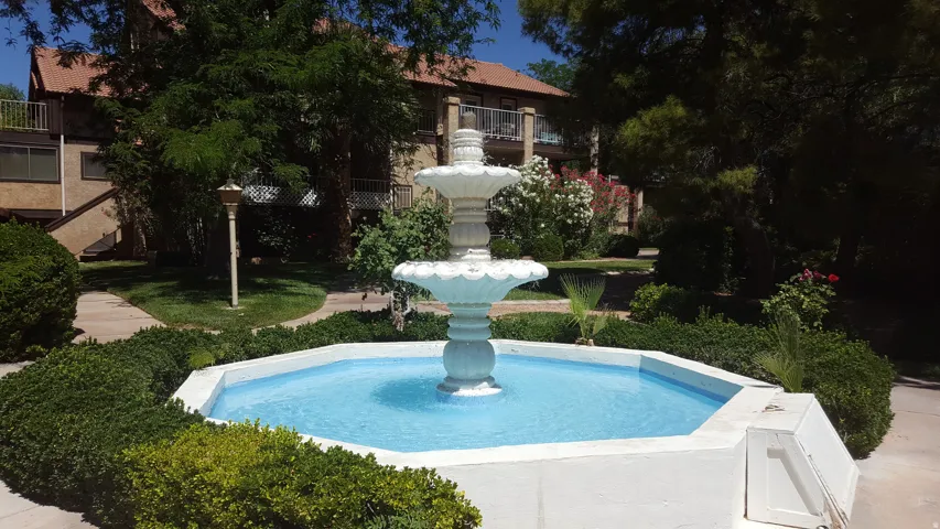 Tiered outdoor fountain with surrounding landscaped greenery and paved walkways
