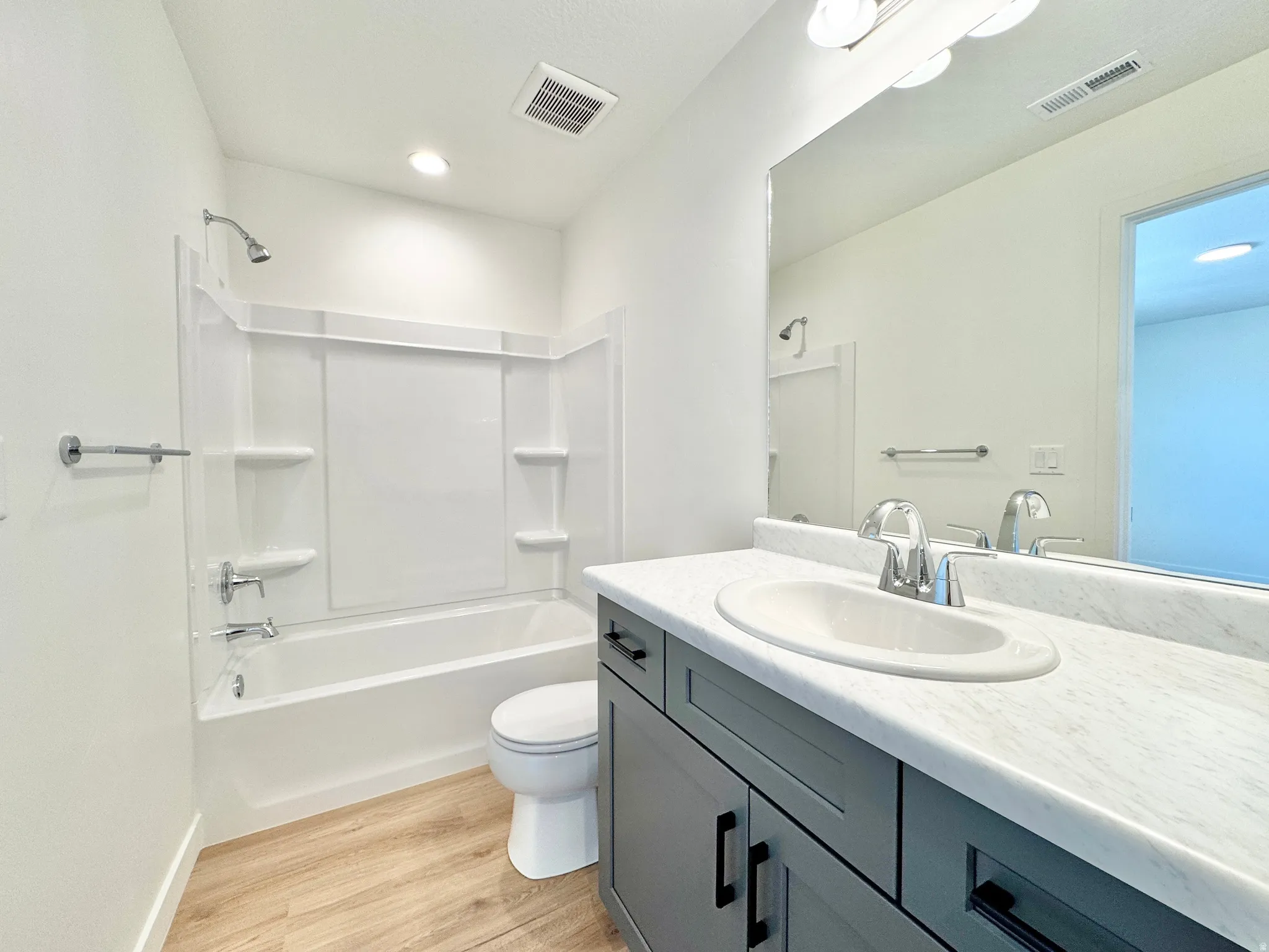 Spa-inspired primary bathroom featuring a dual-sink vanity with wood cabinetry and white quartz countertops, chrome faucet fixtures, and an oversized soaking tub with integrated shower enclosure and tile surround