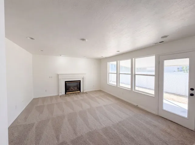 Fireplace with a white mantel, multiple windows, recessed lighting, and a glass-paneled door