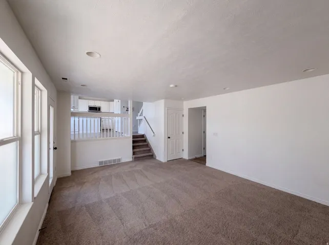 Spacious upper-level living area featuring neutral carpet flooring, recessed ceiling lighting, and abundant natural light from large windows