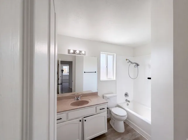 Contemporary bathroom featuring a dual-sink vanity with ample storage, wood-finish countertop, and chrome hardware