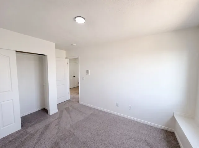 Neutral tone wall paint, recessed ceiling lighting, textured carpet flooring, built-in window bench, and a sliding door closet