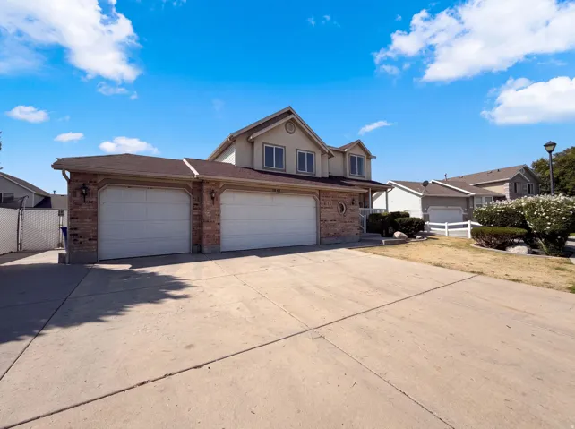 Two-story residence featuring a brick and stucco exterior, an attached two-car garage with individual doors, and a concrete driveway
