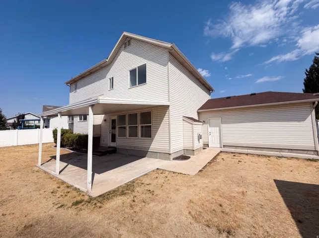 Two-story residence with cream-colored vinyl siding and gabled roofline, featuring a covered front porch with concrete foundation