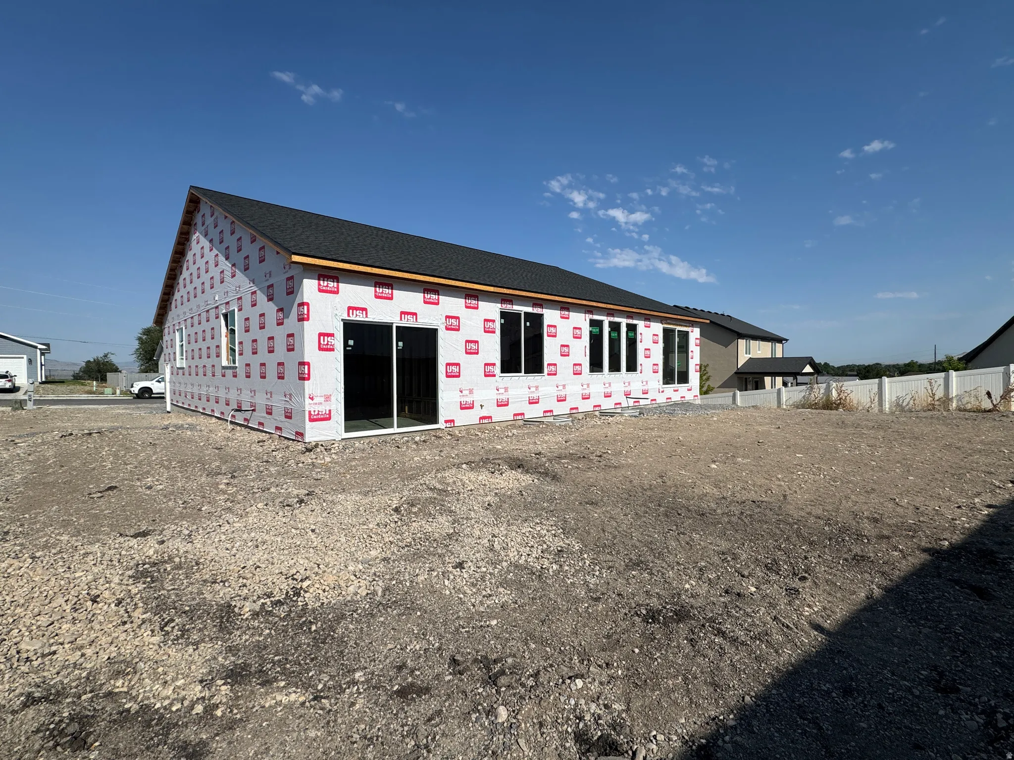 New construction with a dark shingle roof, multiple windows, and a sliding glass door
