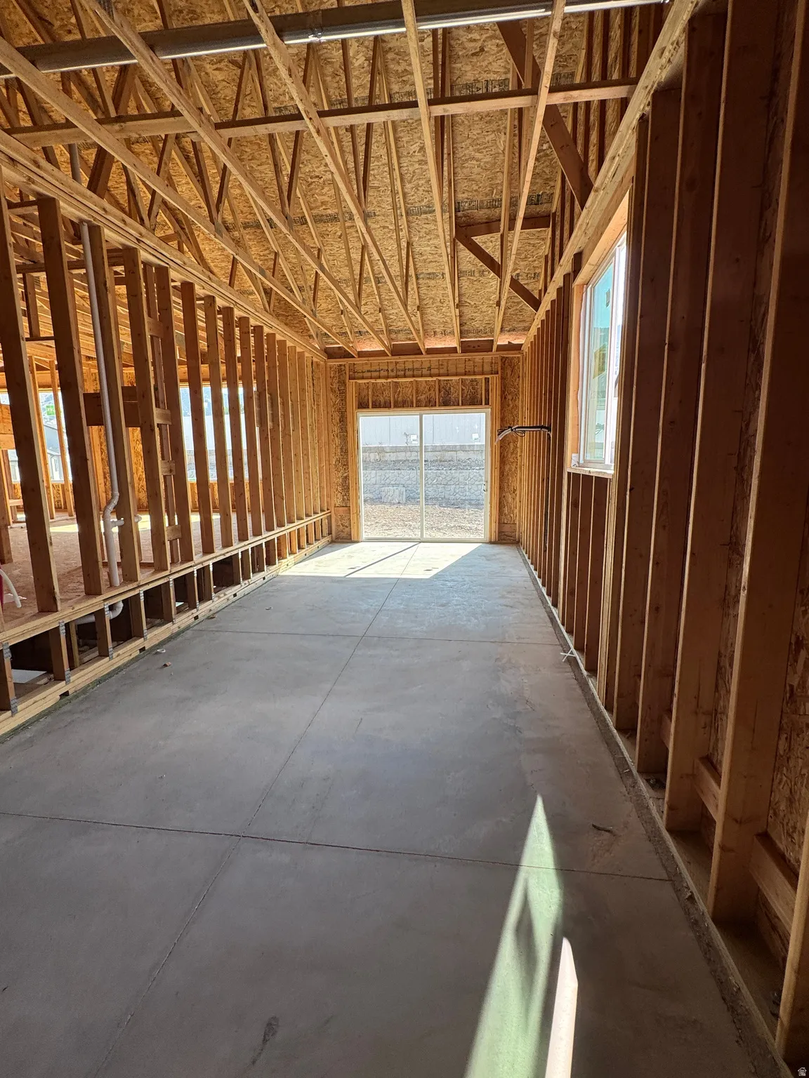 Spacious interior framing with exposed wood-beam ceiling structure, concrete flooring, and abundant natural light from multiple openings