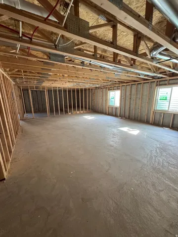 Spacious open interior with concrete flooring, exposed wood beam ceiling structure, and metal stud framing throughout