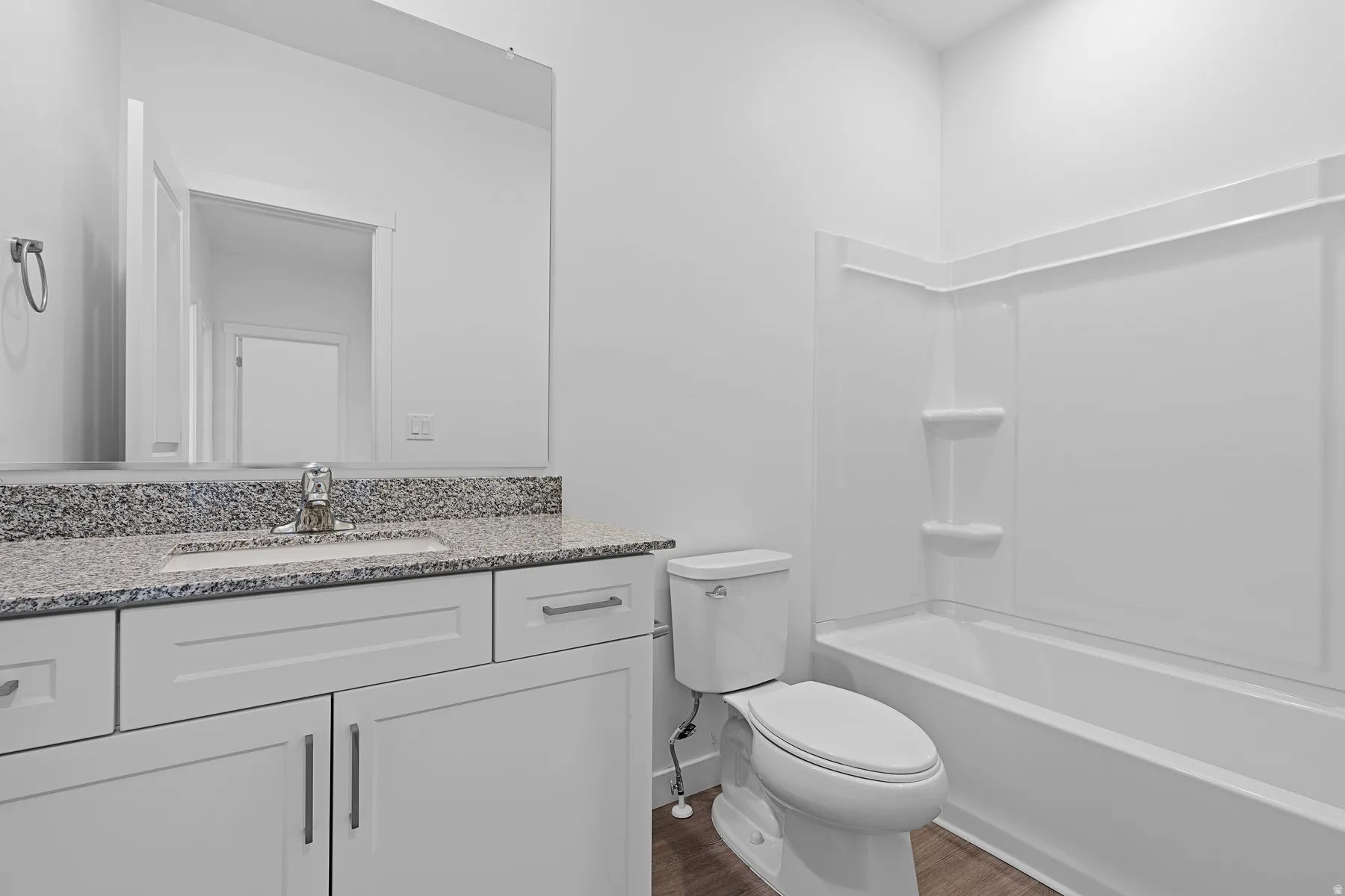 White vanity with granite-finish countertop, undermount sink, and chrome faucet