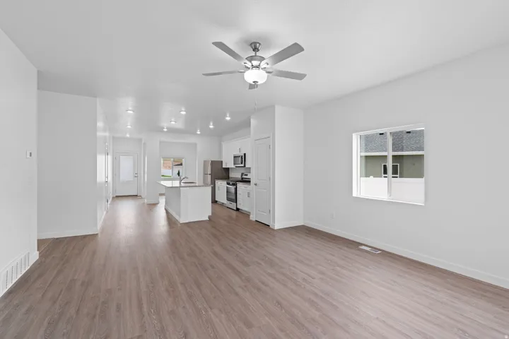 Open-concept living area with wood-finish flooring, recessed lighting, and a ceiling fan