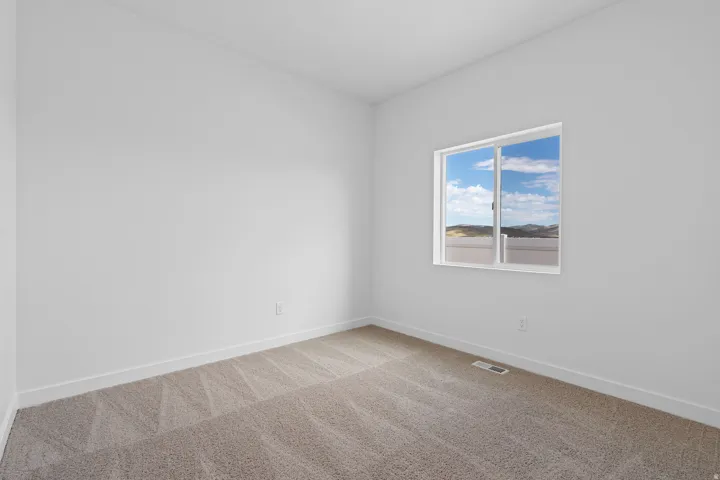 Bright bedroom featuring neutral wall finishes, wood-finish flooring, and a large window framed in white trim offering natural light and expansive outdoor vistas