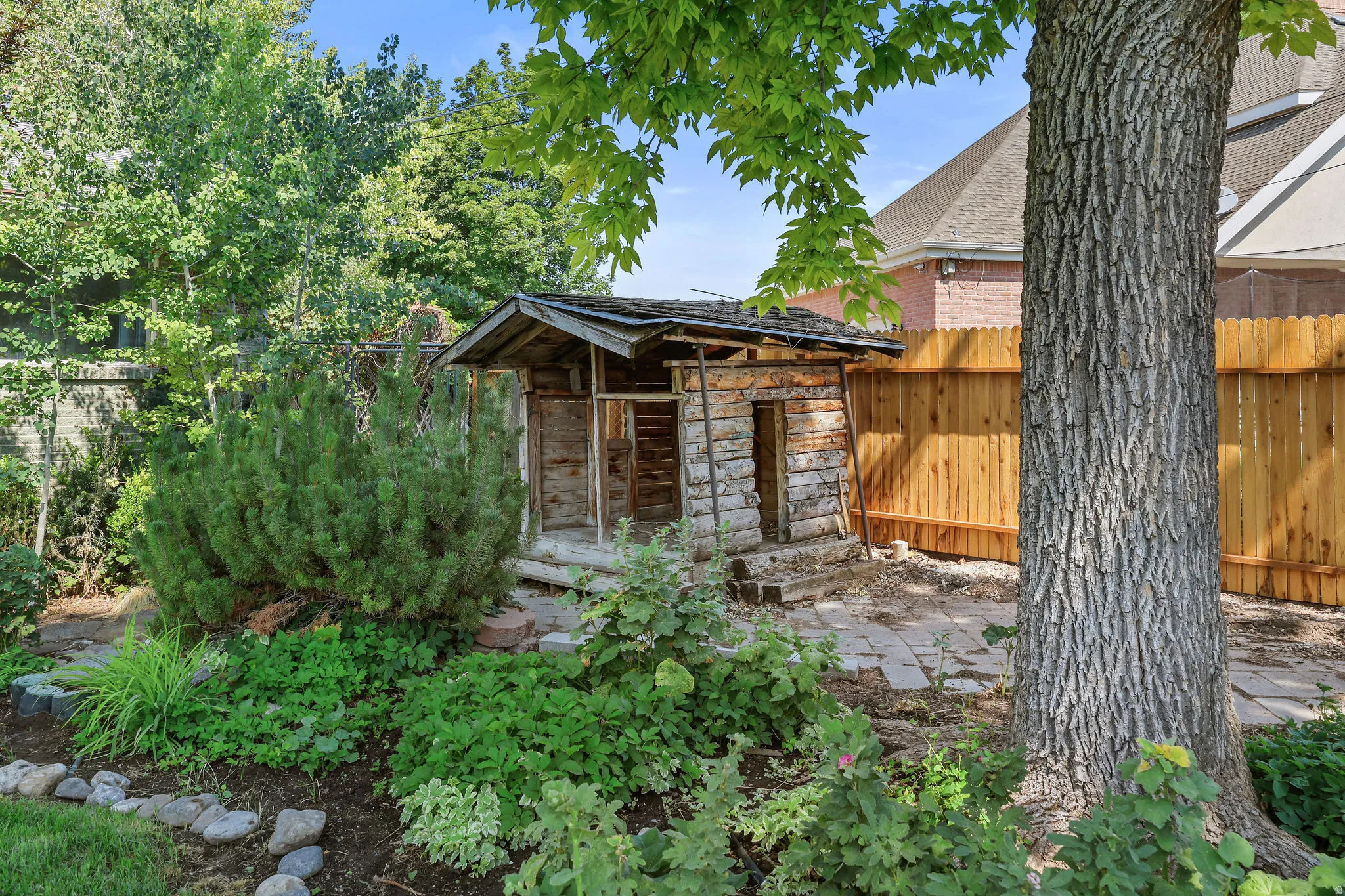 Landscaped yard with a wooden shed, mature trees, and a privacy fence