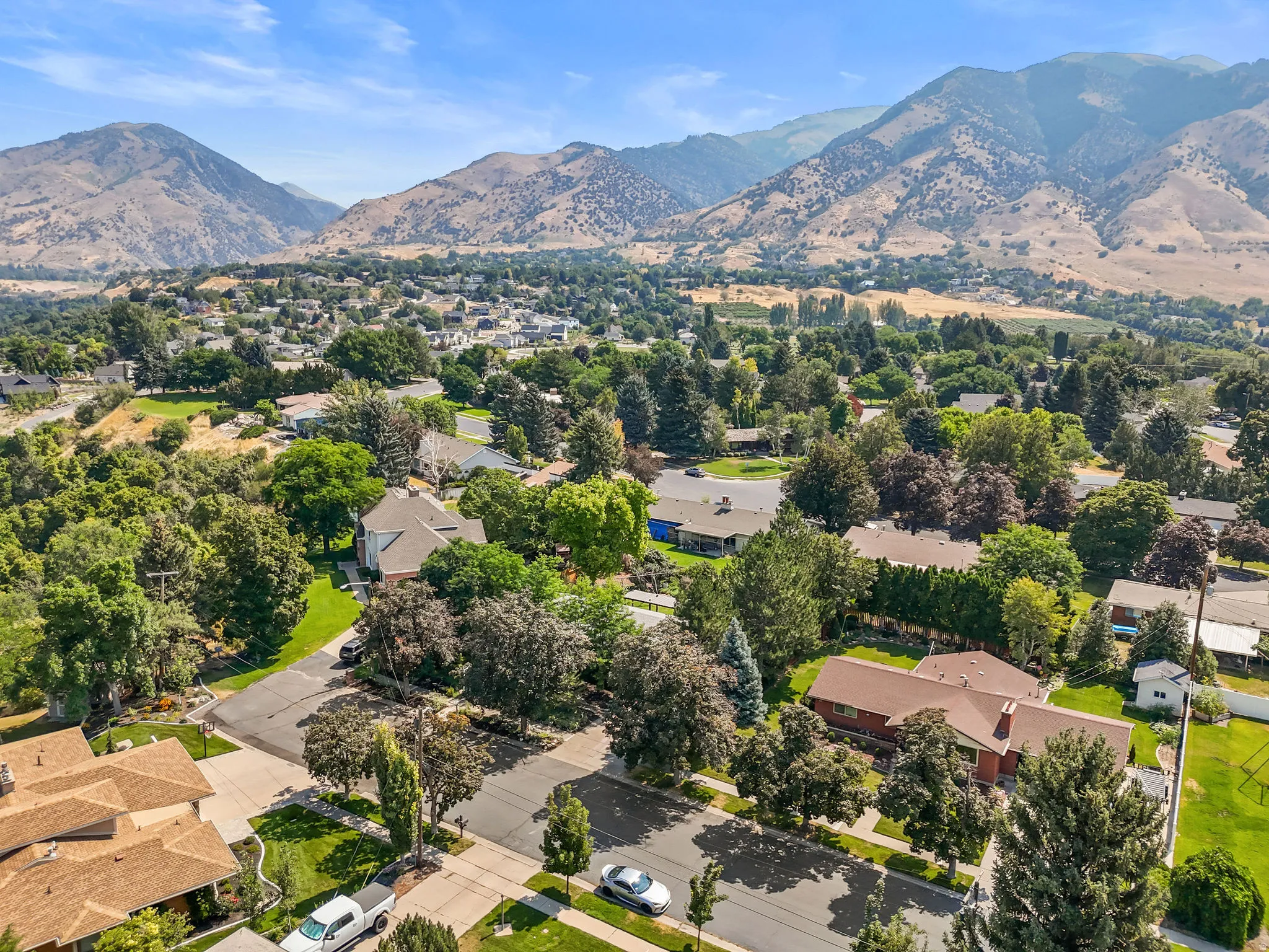 Mountain backdrop, residential neighborhood setting, mature trees, paved streets, and a mix of architectural styles
