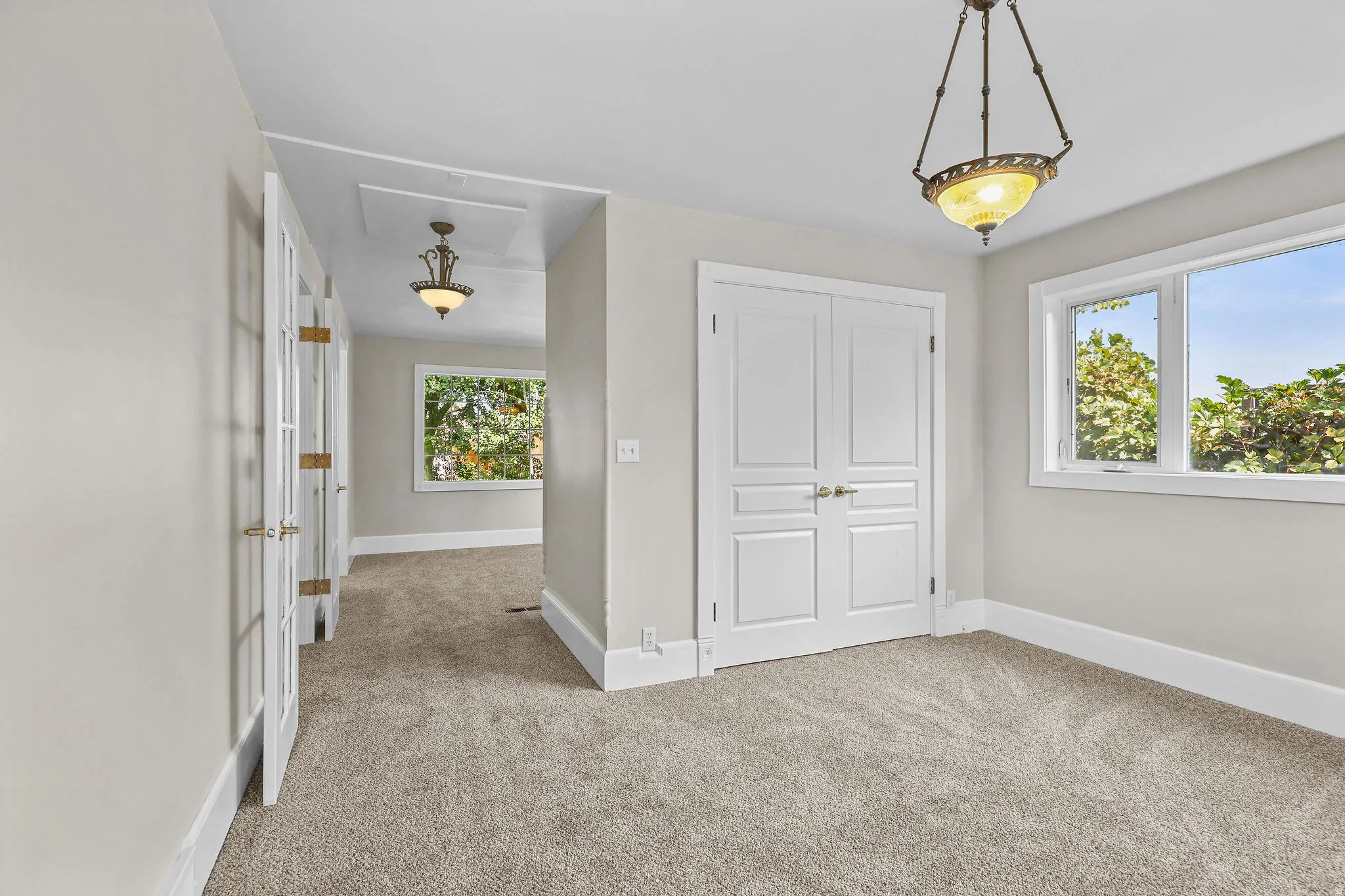 Plush carpet flooring, dual pane windows, elegant ceiling light fixture, and white paneled doors