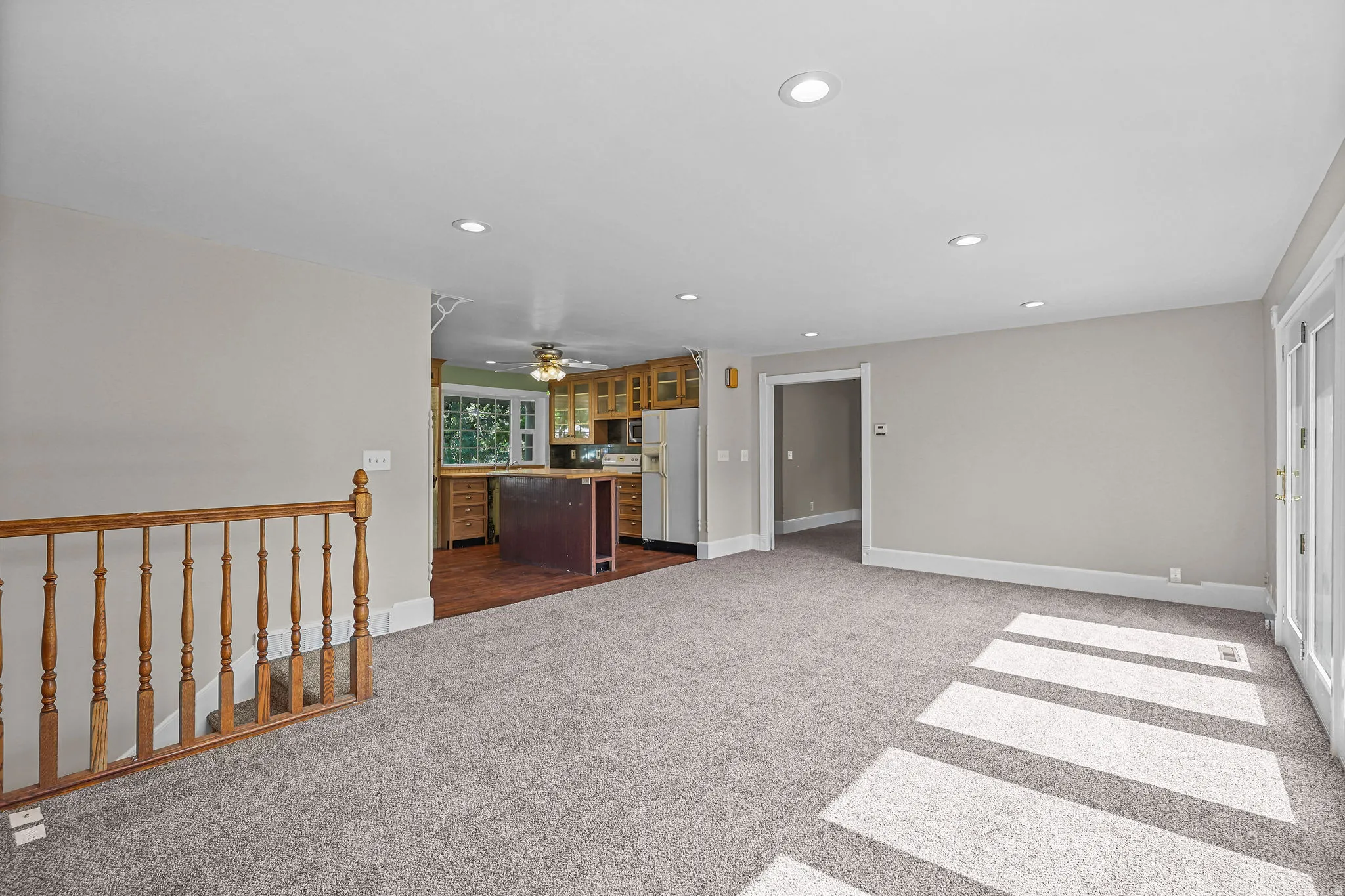 Recessed lighting, light gray wall paint, wood railing, wood-finish flooring in kitchen, and glass-paneled double doors