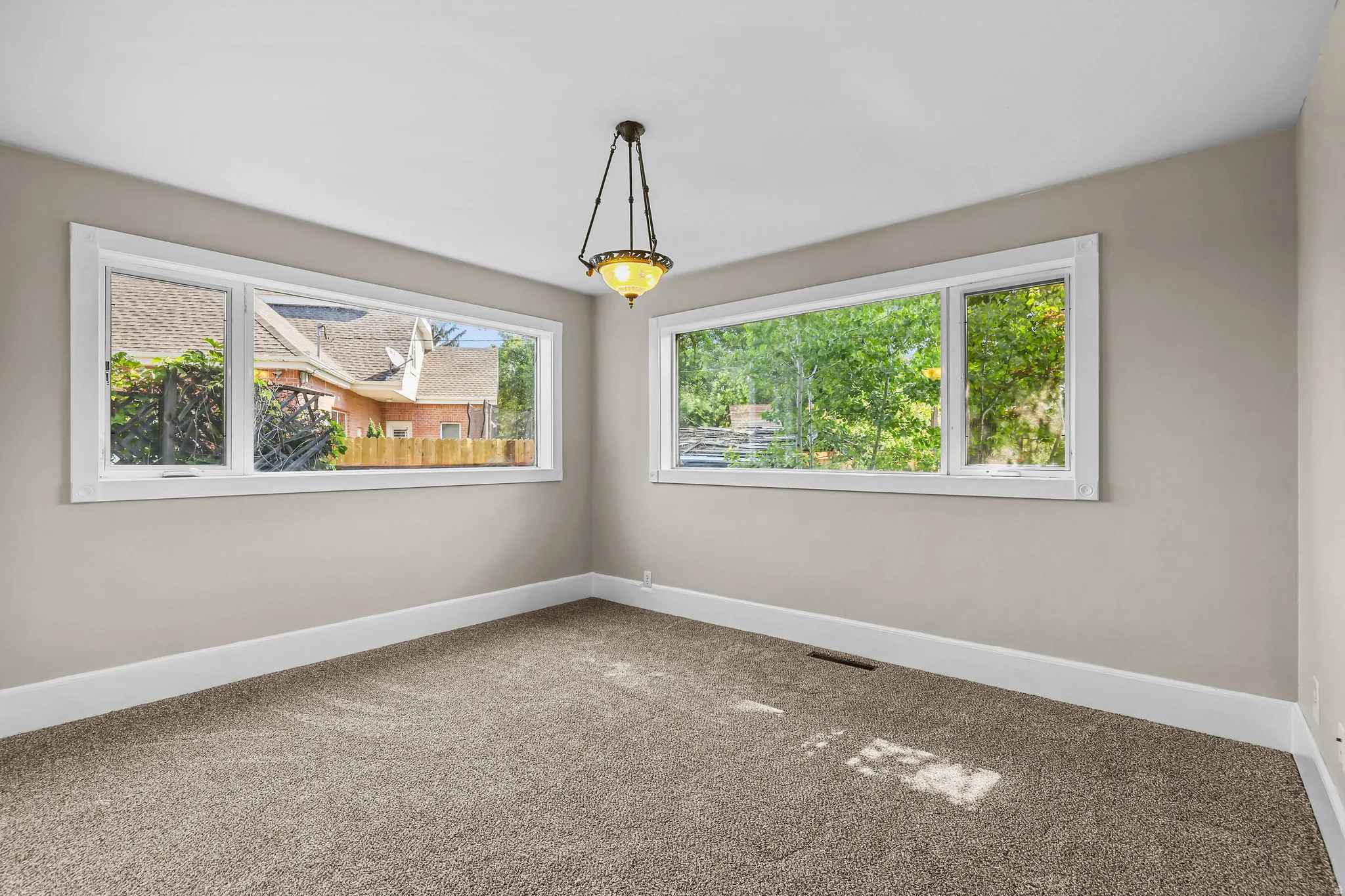 Neutral-toned walls with contrasting white trim, plush carpeting, and two expansive windows providing natural illumination