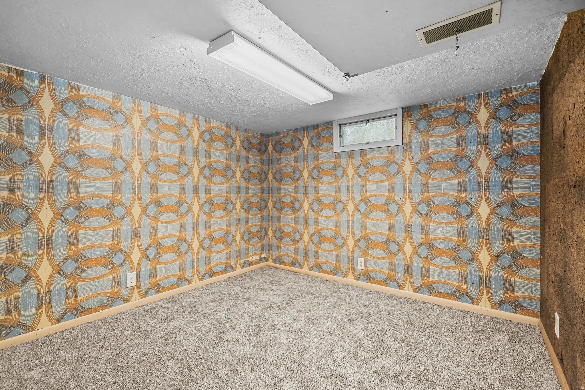 Textured wallcovering with a geometric pattern, neutral carpet flooring, and a flush-mount ceiling light fixture