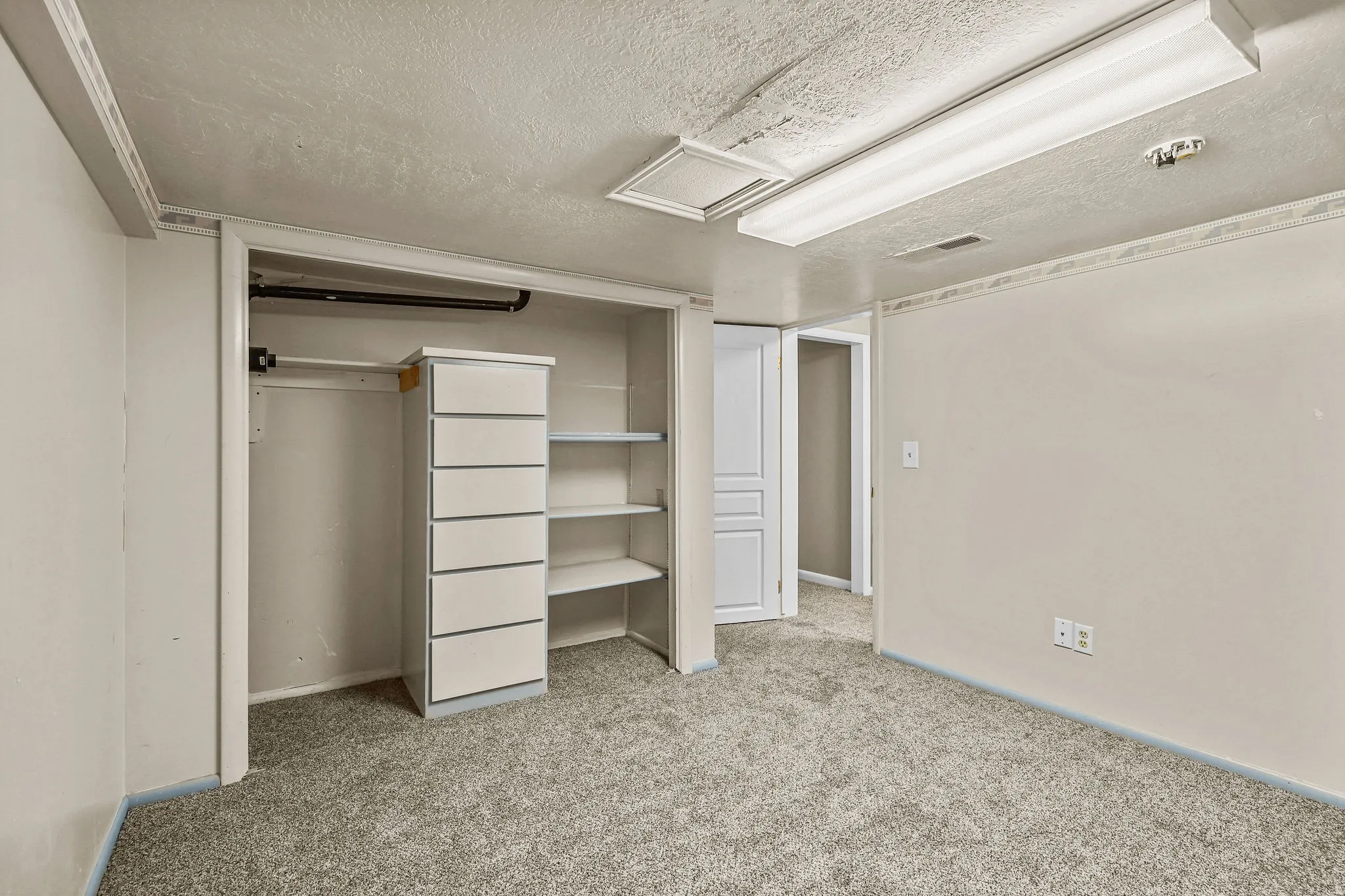 Spacious primary closet featuring built-in shelving and hanging storage, carpeted flooring, and recessed ceiling lighting for optimal organization and visibility