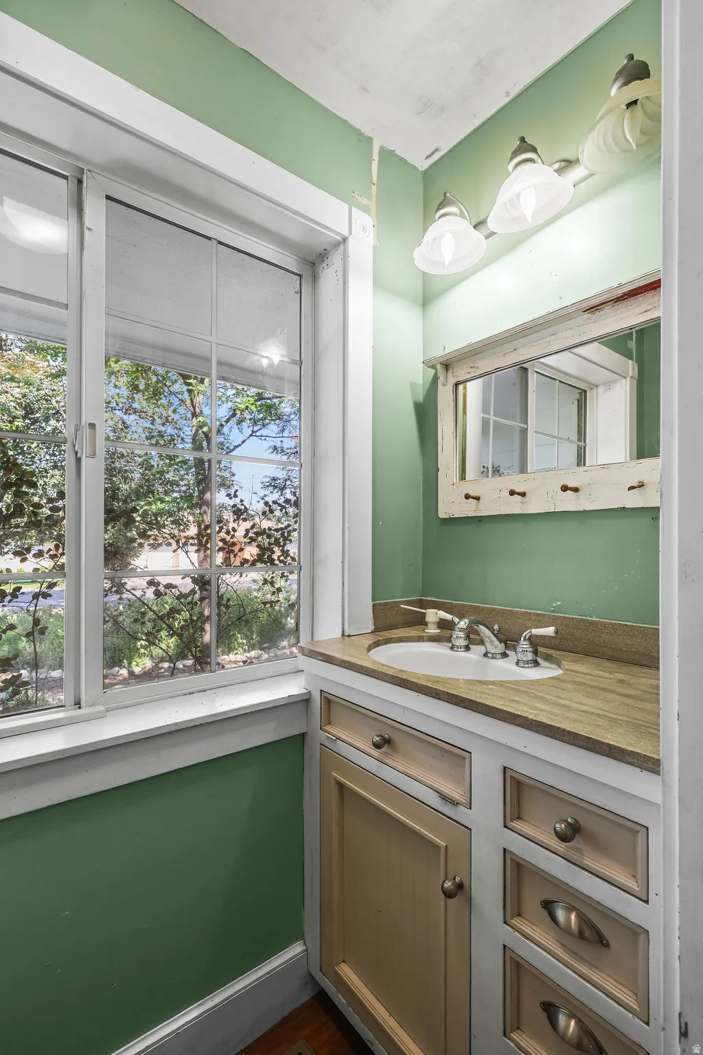 Windowed vanity area featuring an undermount sink, dual handle faucet, and integrated wood-finish countertop