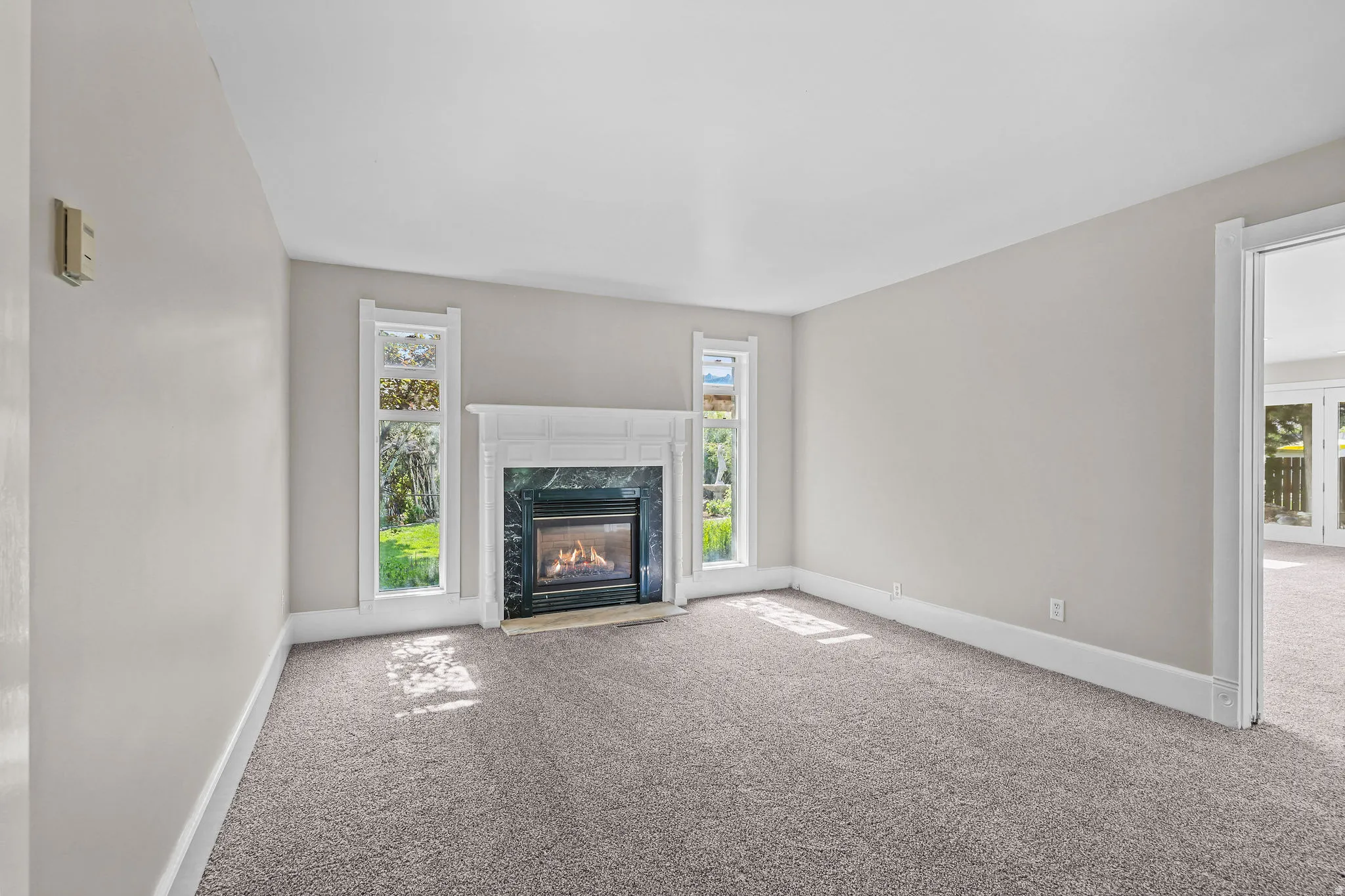 Fireplace with a decorative white mantel, dark stone surround, and light carpet flooring