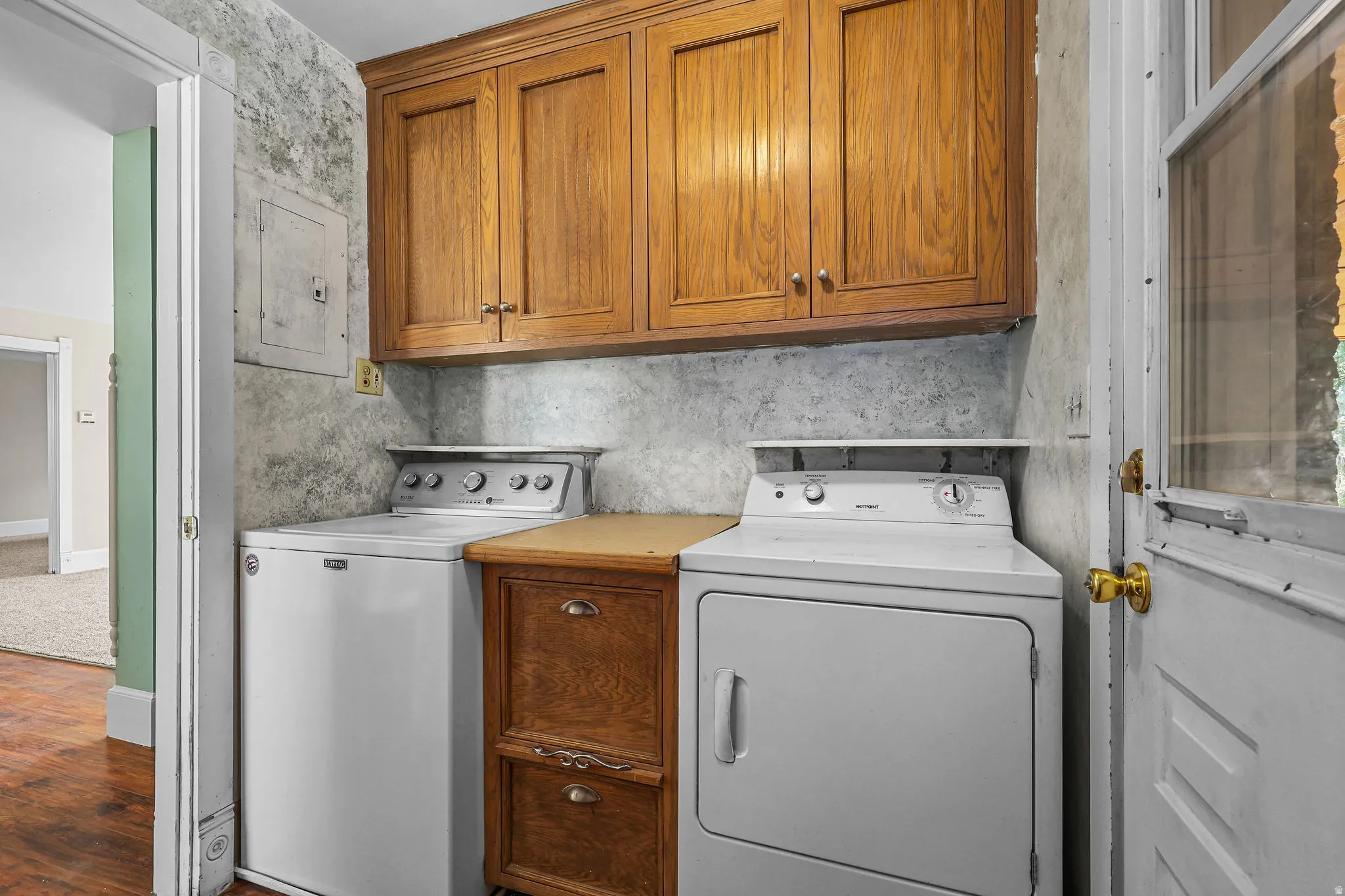 Laundry area with wood-finish upper cabinetry and a built-in wood-finish cabinet