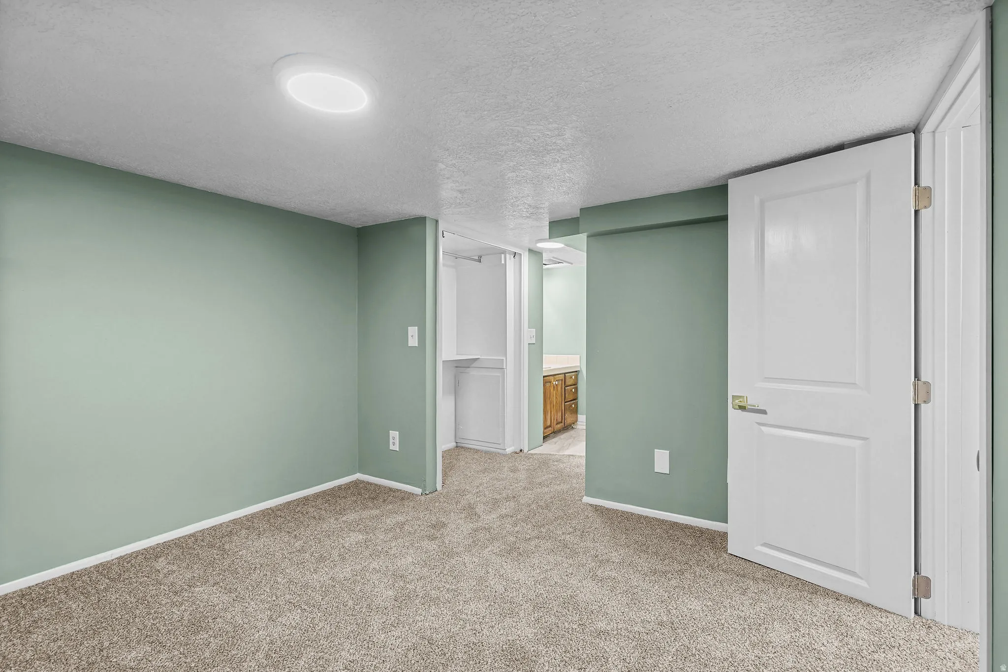 Recessed ceiling lighting, textured carpet flooring, and white trim