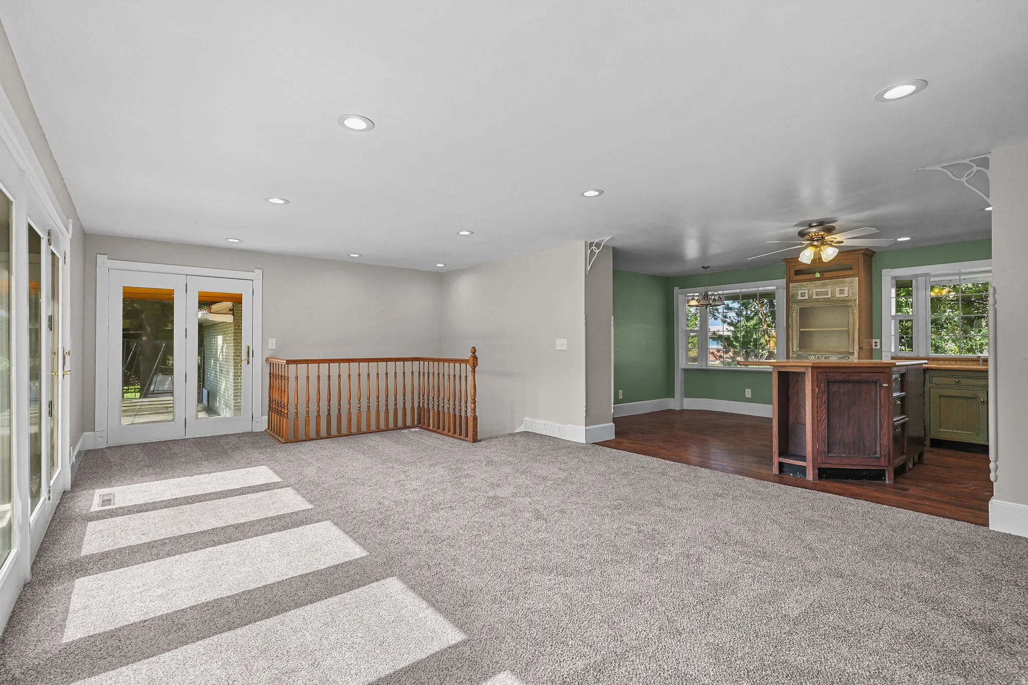 Recessed lighting, wood-finish flooring, light grey carpeting, painted wood balusters, and transom windows