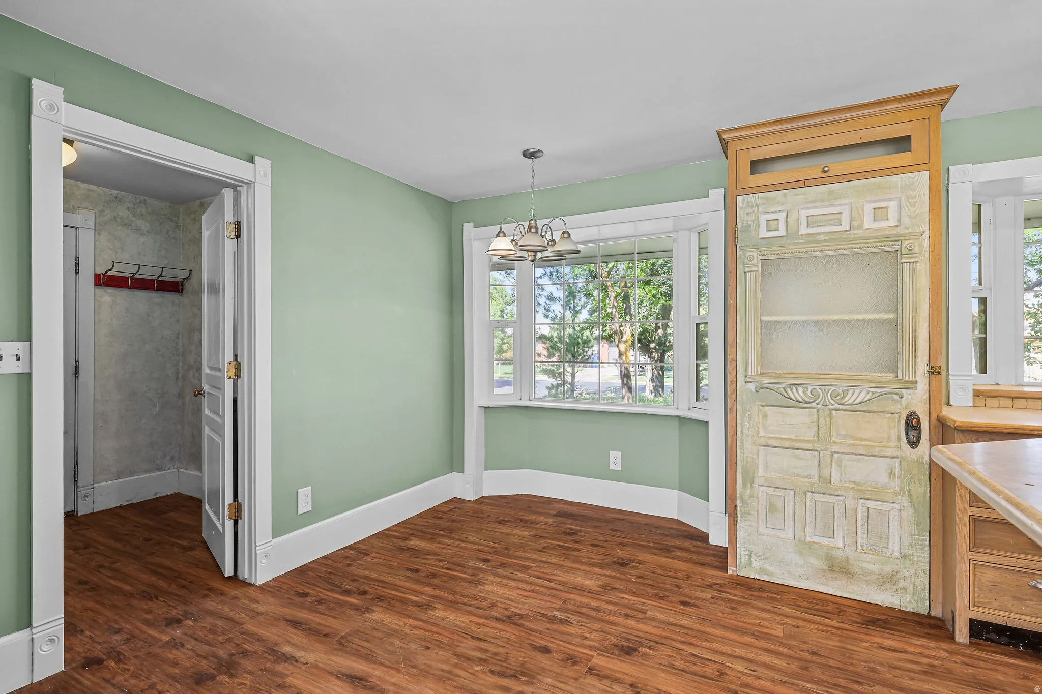 Wood-finish flooring, bay windows, built-in display cabinet, and a chandelier