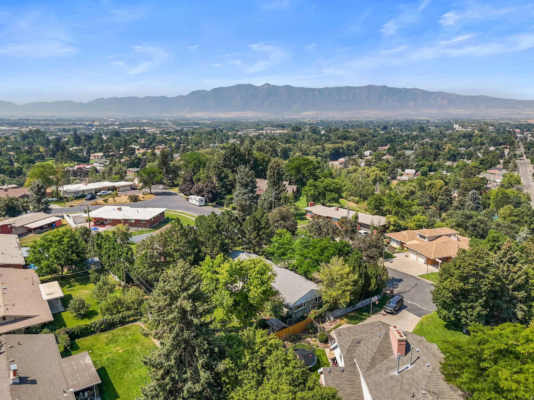 Expansive suburban setting with established trees and mountain backdrop