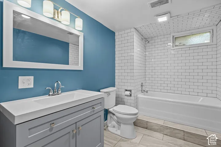 Modern bathroom featuring a striking teal accent wall, white subway tile surround, and a gray vanity with a white quartz countertop and chrome faucet