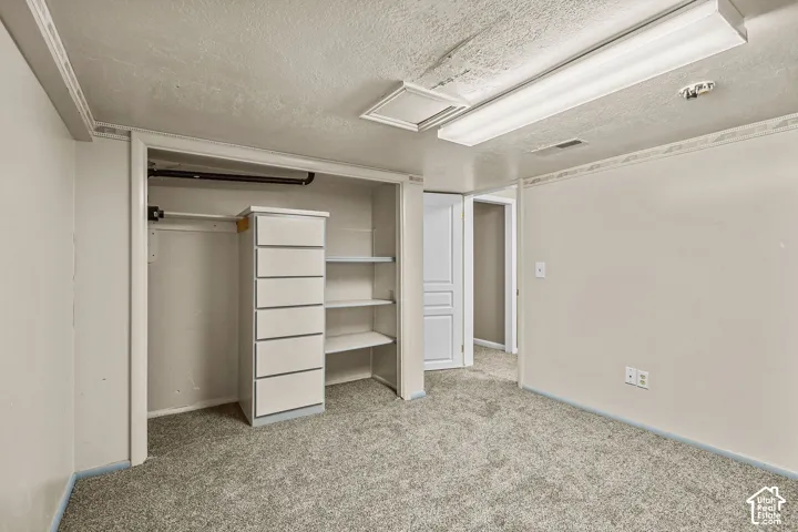 Spacious primary closet featuring built-in shelving and hanging storage, carpeted flooring, and recessed ceiling lighting for optimal organization and visibility