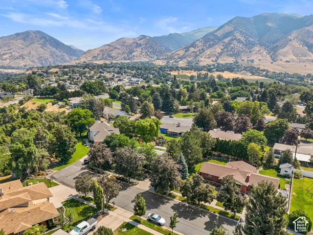Mountain backdrop, residential neighborhood setting, mature trees, paved streets, and a mix of architectural styles